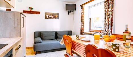Un rincón comedor acogedor con un mantel a cuadros, una silla de madera y una botella de vino sobre la mesa.
