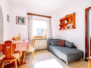 Ein gemütliches Wohnzimmer mit Esstisch, einer Couch und einem Fenster mit Vorhängen.