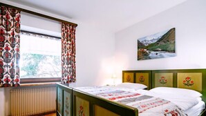 Un dormitorio con cama, un radiador, una ventana con cortinas y un cuadro en la pared.