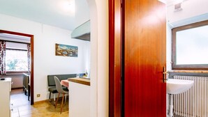 Una habitación compacta con comedor, una pequeña kitchenette y un baño.