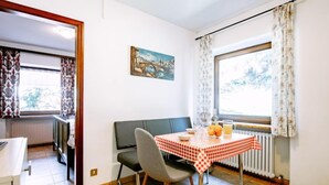 Un comedor con una mesa para dos, un sofá y una ventana con cortinas.