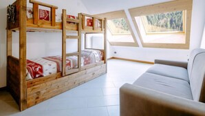 Ein Zimmer mit Etagenbett, einer Schlafcouch und Dachfenstern.