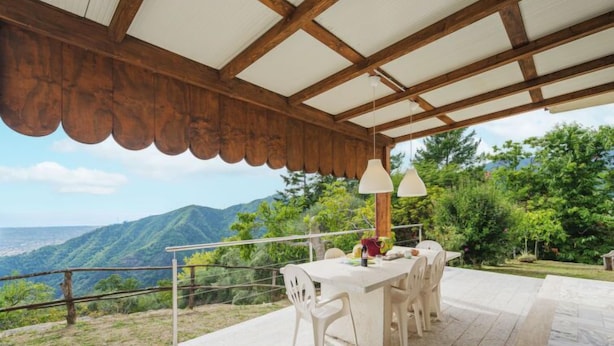 An outdoor dining area with a table and chairs, a pergola overhead, and a scenic view of mountains. - Casa Giulia by Interhome (Seravezza)
