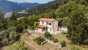 A two-story house with a balcony, surrounded by lush greenery and mountains in the background. - Casa Giulia by Interhome (Seravezza)