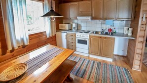 Eine kleine Küche mit Holzausstattung, einer Mikrowelle, einem Herd und einem Spülbecken.