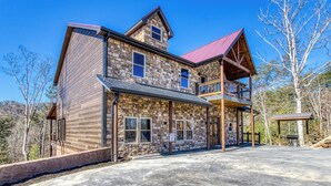A two-story stone building with a red roof and a balcony. - HIBERNATION STATION - 12 Bedrooms with a pool! (Sevierville)