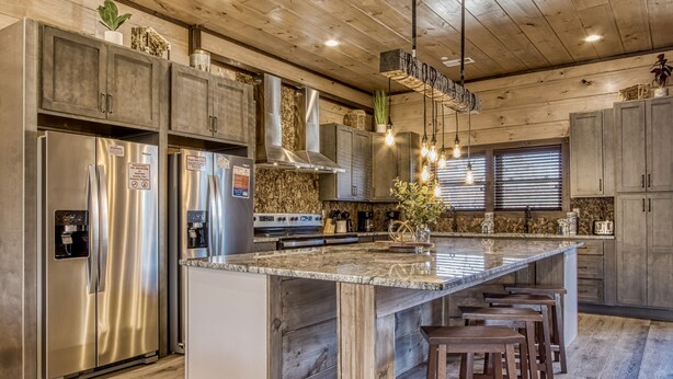 A modern kitchen with a large island, stainless steel appliances, and wooden cabinetry. - HIBERNATION STATION - 12 Bedrooms with a pool! (Sevierville)