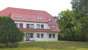 Un bâtiment à deux étages, doté d’un toit recouvert de tuiles rouges, de nombreuses fenêtres et d’une entrée principale avec une porte et un petit porche.