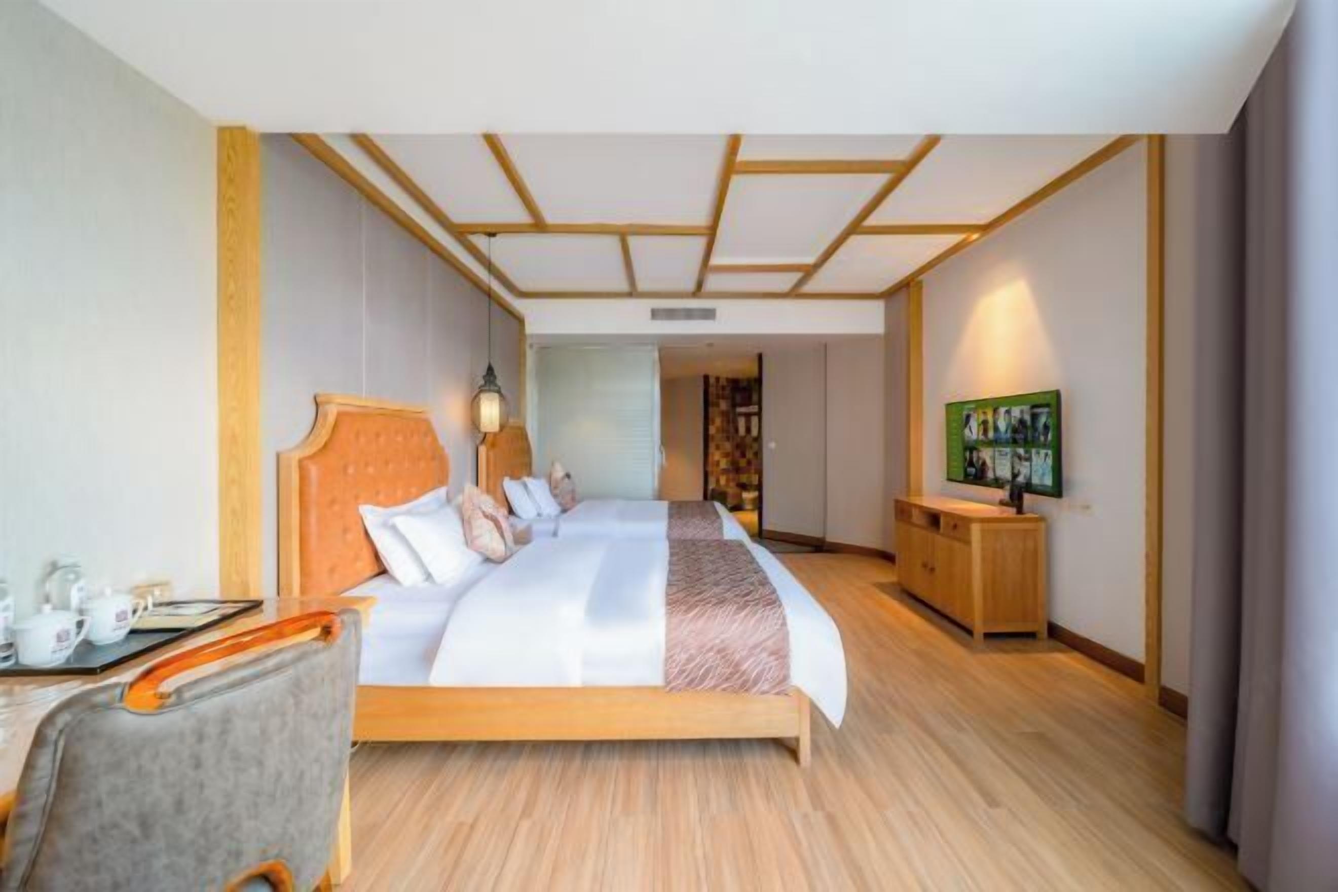Habitación de hotel con cama, mesita de noche, lámpara y vista al pasillo.