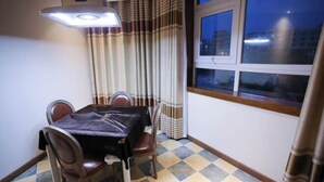 Un comedor con una mesa y sillas, una ventana con cortinas y un piso a cuadros.