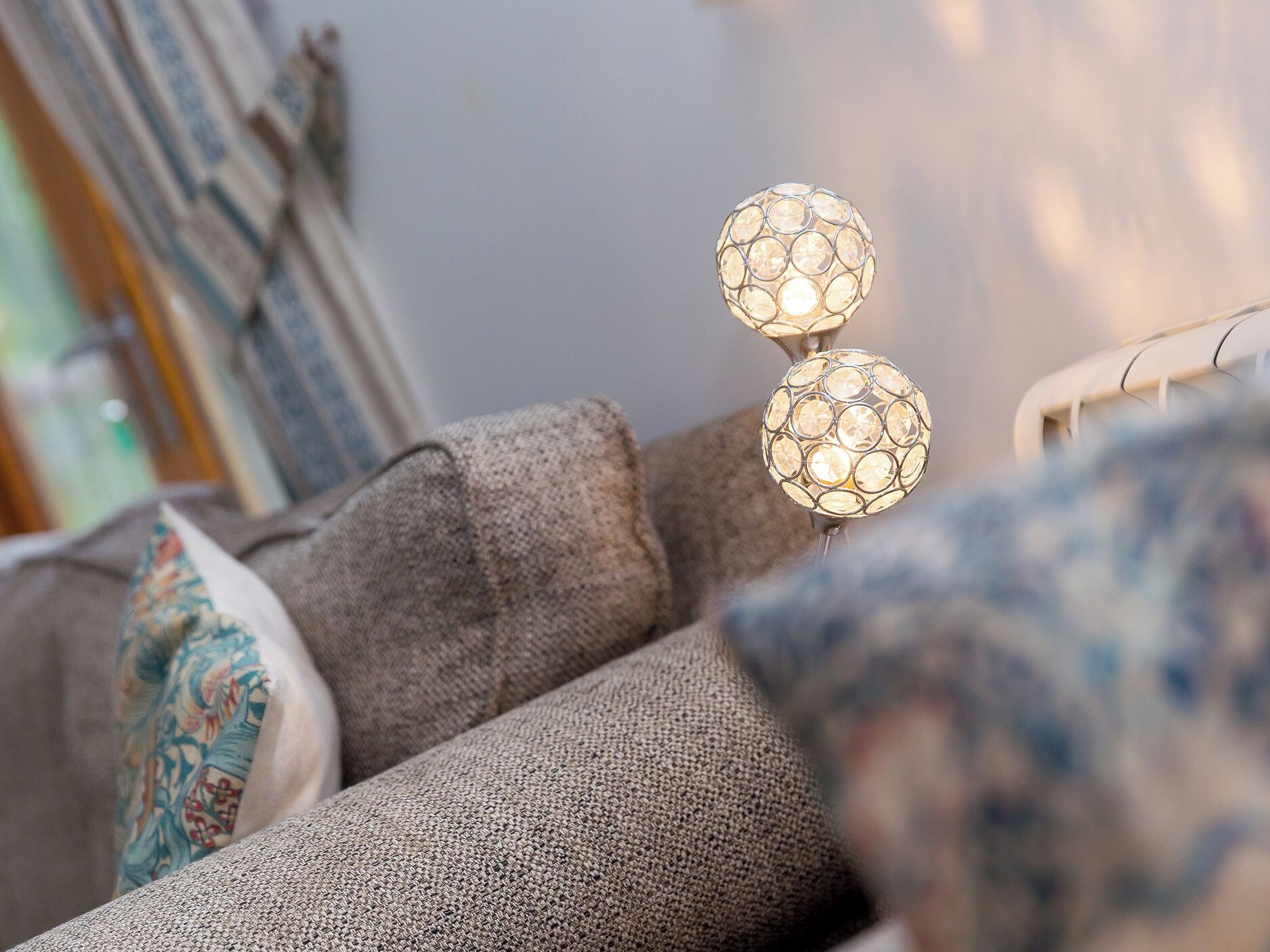 A textured sofa with a decorative pillow and a wall-mounted spherical light fixture.