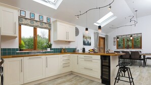 Una cocina moderna con una isla central, un comedor con mesa y sillas, y vistas al exterior.