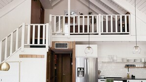 A spacious kitchen with a high ceiling, a central island, and a mezzanine level with a balcony. - White Mtns Cabin | Balcony | Fireplace | Grill (Pinetop)