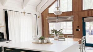 A modern kitchen with a large island, pendant lights, and large windows. - White Mtns Cabin | Balcony | Fireplace | Grill (Pinetop)