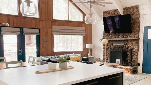 A spacious kitchen with a large island, wooden walls, and a stone fireplace. - White Mtns Cabin | Balcony | Fireplace | Grill (Pinetop)