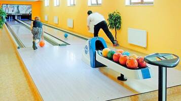 Bolera con carriles, una bola de bolos y un lanzador de bolos.