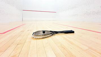 Una cancha de squash con suelo de madera y una raqueta de squash.