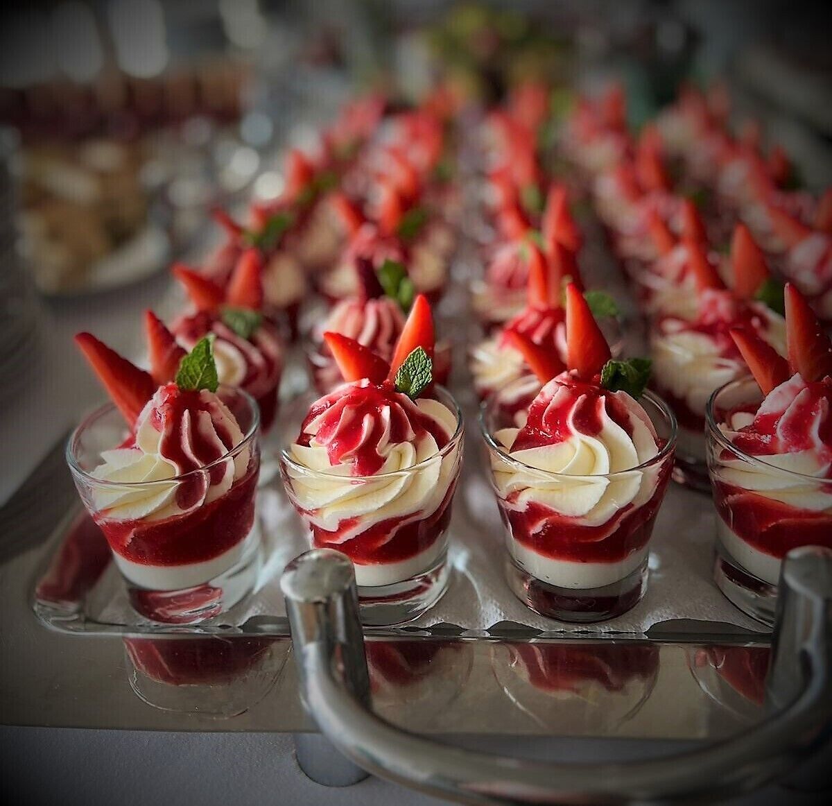 Eine Auswahl an Dessertgläsern mit Schlagsahne und Erdbeeren.
