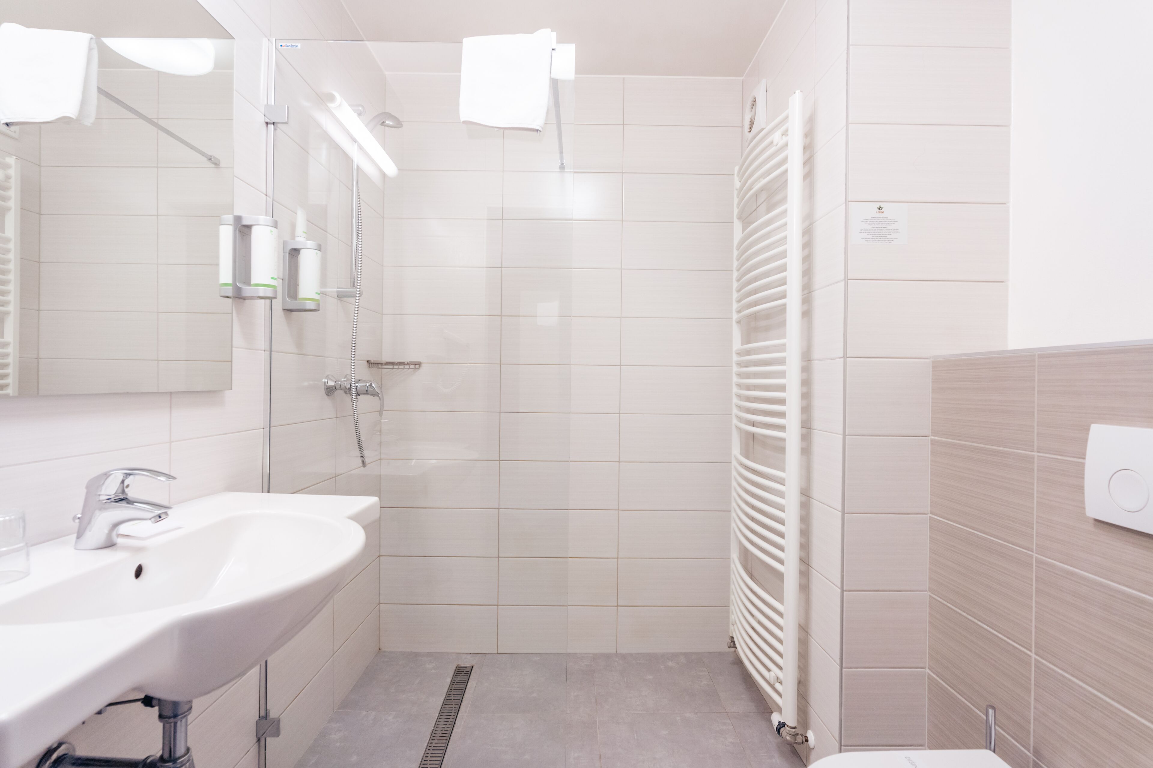 Un baño moderno con lavamanos, espejo y ducha.