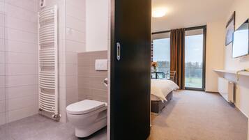 Une salle de bain d’hôtel moderne, équipée de toilettes, d’un radiateur blanc et d’un espace douche.