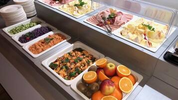 Un bufé con diversas opciones de comida, incluyendo carnes, quesos, frutas y ensaladas.