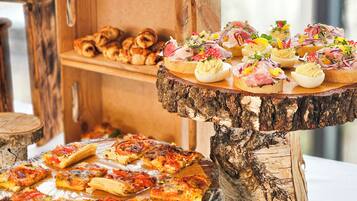 A buffet with various food items, including pizza and appetizers, displayed on wooden stands and a tree stump.
