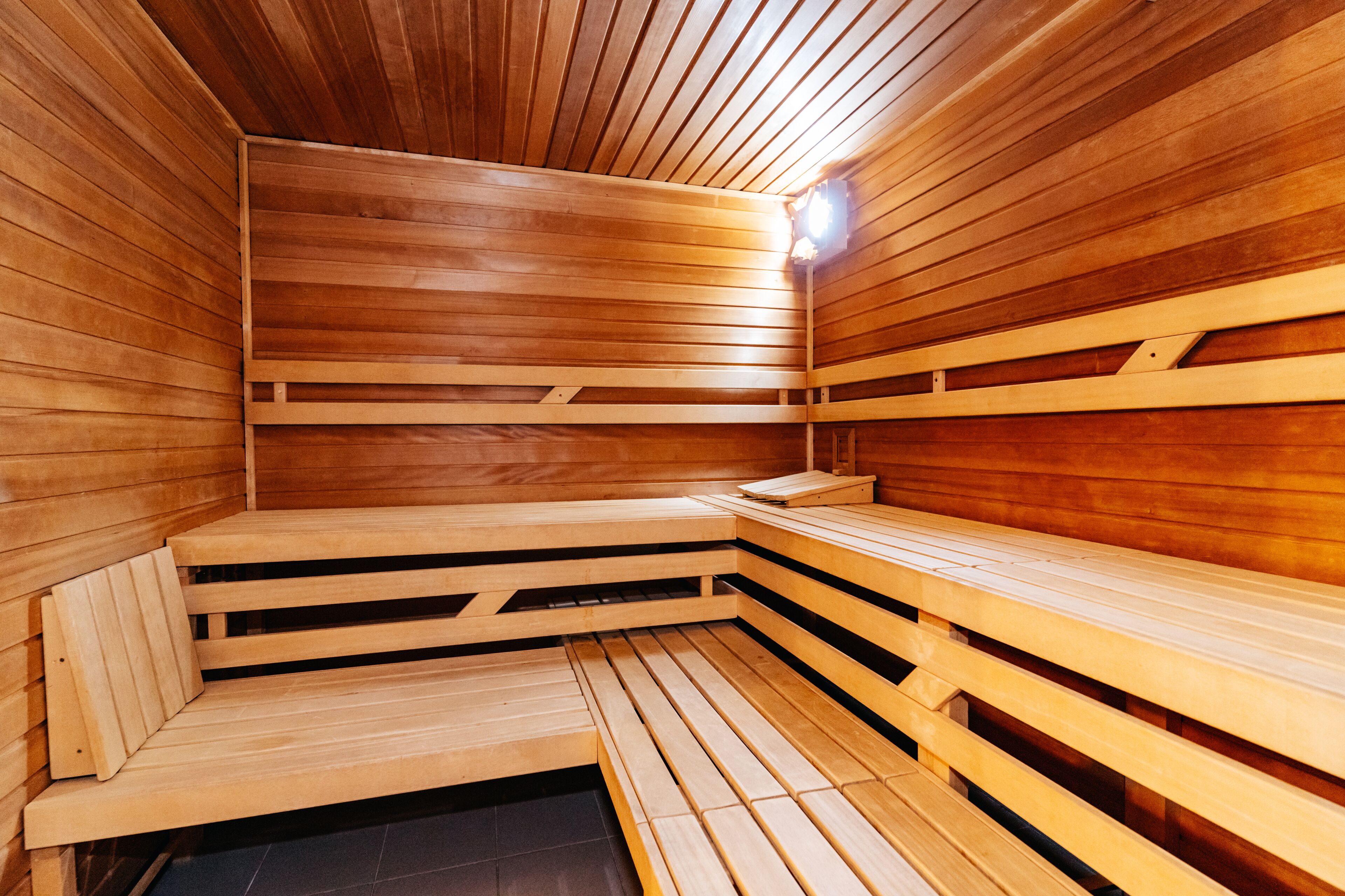 Un sauna avec des bancs en bois et un luminaire.