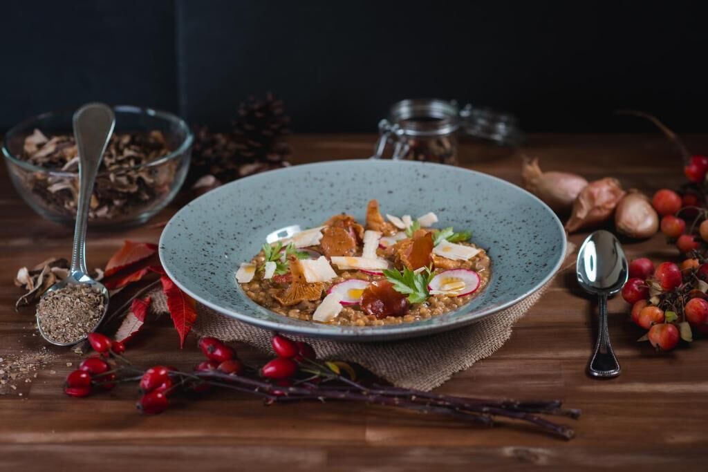 Un tazón de comida con diferentes ingredientes, rodeado de productos y utensilios sobre una mesa de madera.
