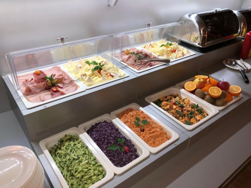 A buffet with various food options including meats, salads, and fruits.