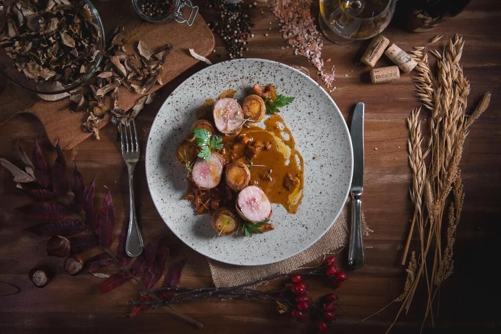 A plate of food with a fork and knife on a wooden table.