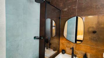 Een moderne badkamer met een douche met glazen wanden, een grote spiegel en een wastafel met een zwarte kraan.