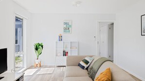 Ett modernt vardagsrum med en soffa, en tv, en bokhylla och en växt.