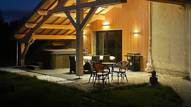 Ein überdachter Außenbereich zum Essen mit einer Holz-Pergola, einem Tisch und Stühlen.