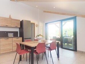 A modern kitchen with wooden cabinets, a refrigerator, and a dining area with a table and chairs.