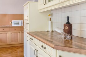 A kitchen with wooden cabinets, a microwave, a wine bottle, and a roll of paper towels.