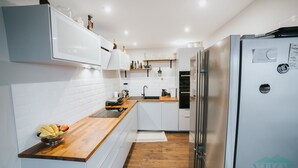 A modern kitchen with white cabinets, a wooden countertop, a stainless steel refrigerator, and a built-in oven. - Enjoy panoramic view of The Little Carpathian (Pezinok)