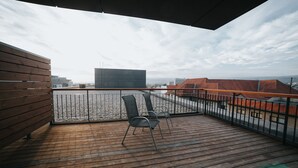 A wooden deck with metal railings, two chairs, and a view of buildings and a cloudy sky. - Enjoy panoramic view of The Little Carpathian (Pezinok)