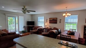 Amplia sala de estar con una isla grande, ventilador de techo, televisor y mesa de comedor con sillas.