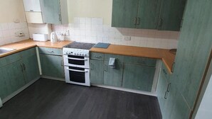 A kitchen with green cabinets, a stove, and a countertop. - 4 Bed House Sleeps 12 - Private Garden - Parking (London)