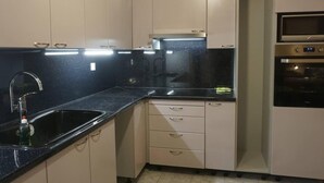 A compact kitchen with a black countertop, a stainless steel sink, and a built-in oven. - Lovely Modern Studio in Romanos Patras, Greece (Patras)