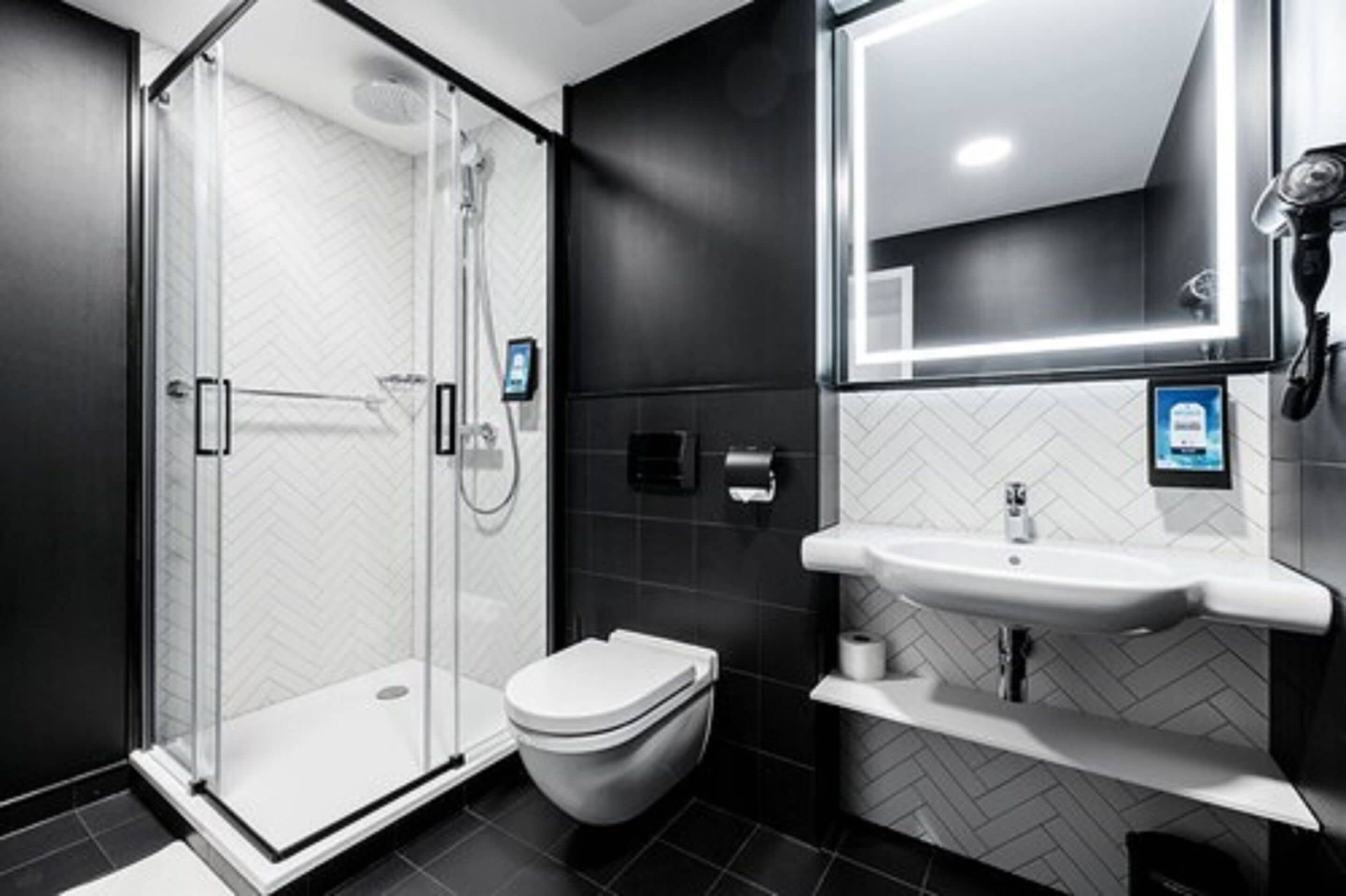 Un baño moderno con cabina de ducha de vidrio, un inodoro y un lavabo con espejo.