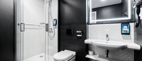 Un baño moderno con cabina de ducha de vidrio, un inodoro y un lavabo con espejo.