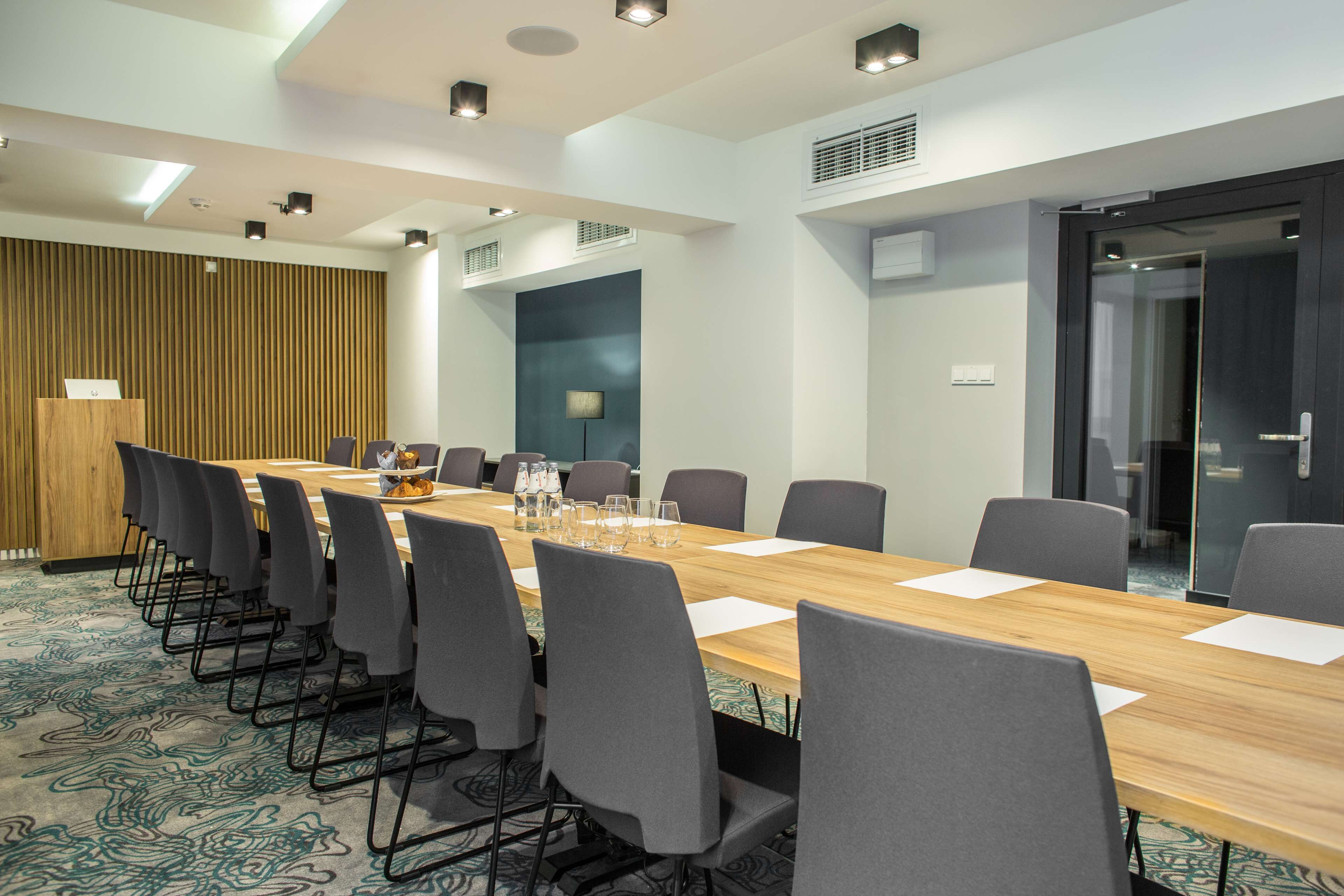A conference room with a long table, chairs, and a wooden panel wall.