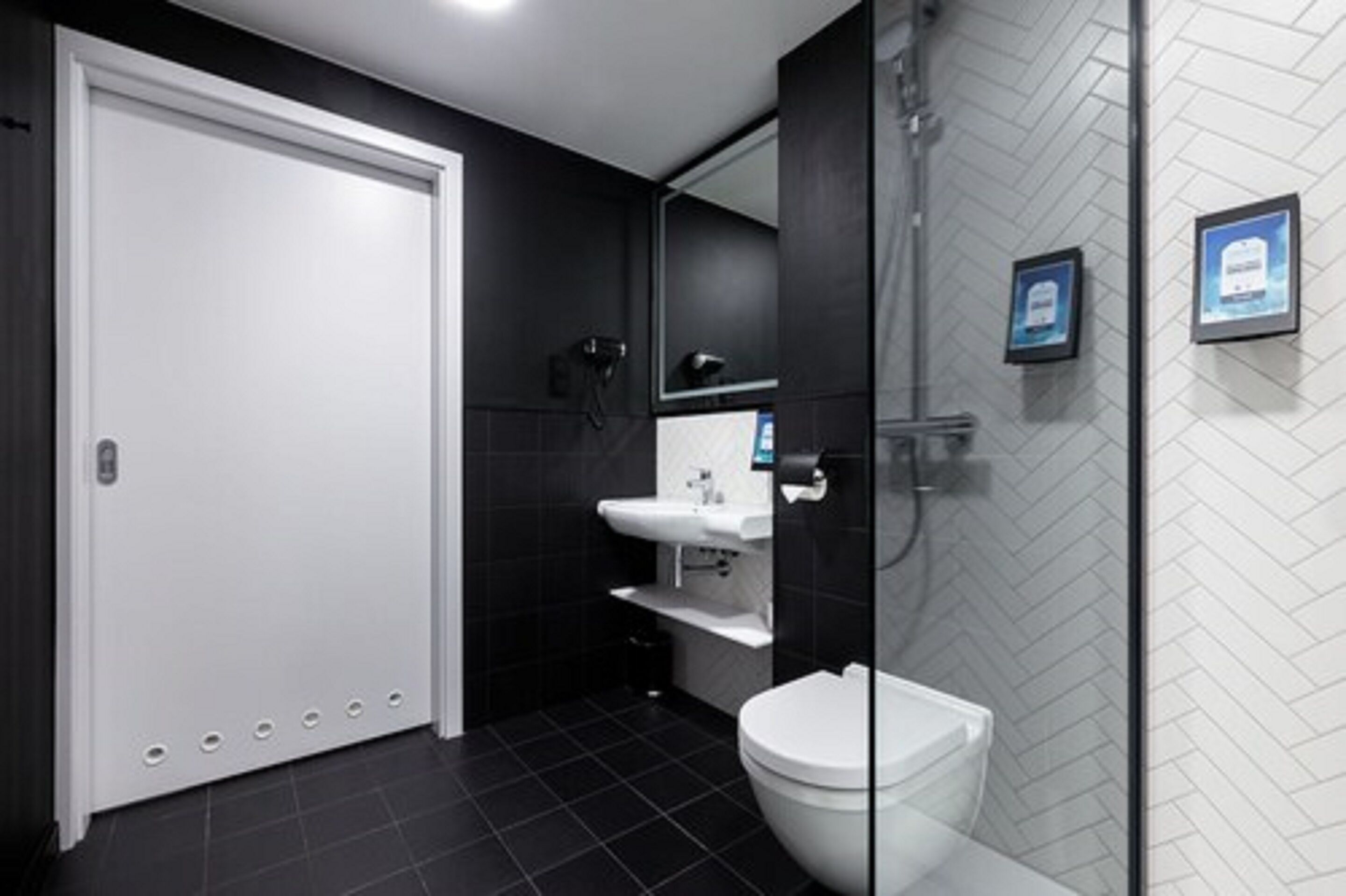 Un baño moderno con inodoro blanco, lavamanos y zona de ducha.