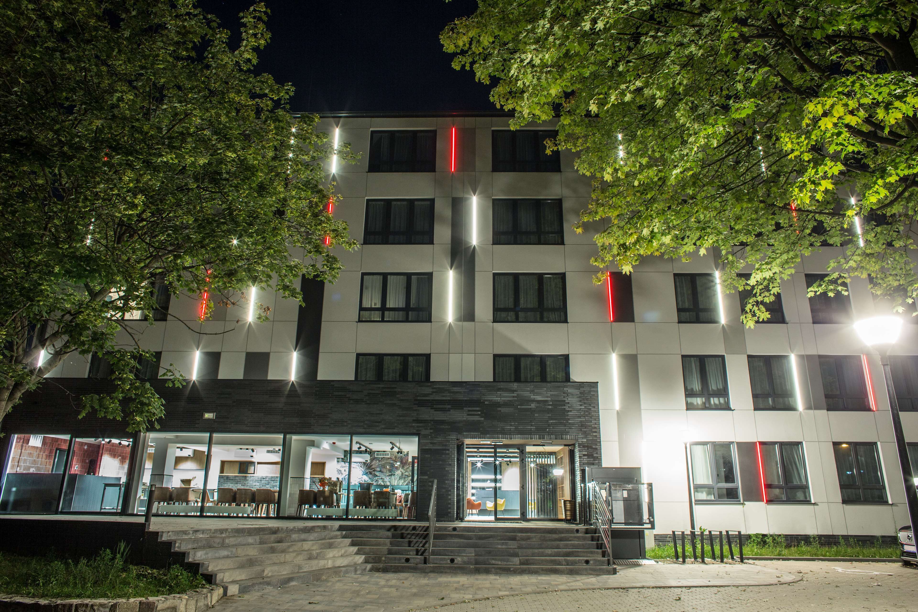 Um edifício moderno com fachada de vidro e uma escadaria que leva à entrada.