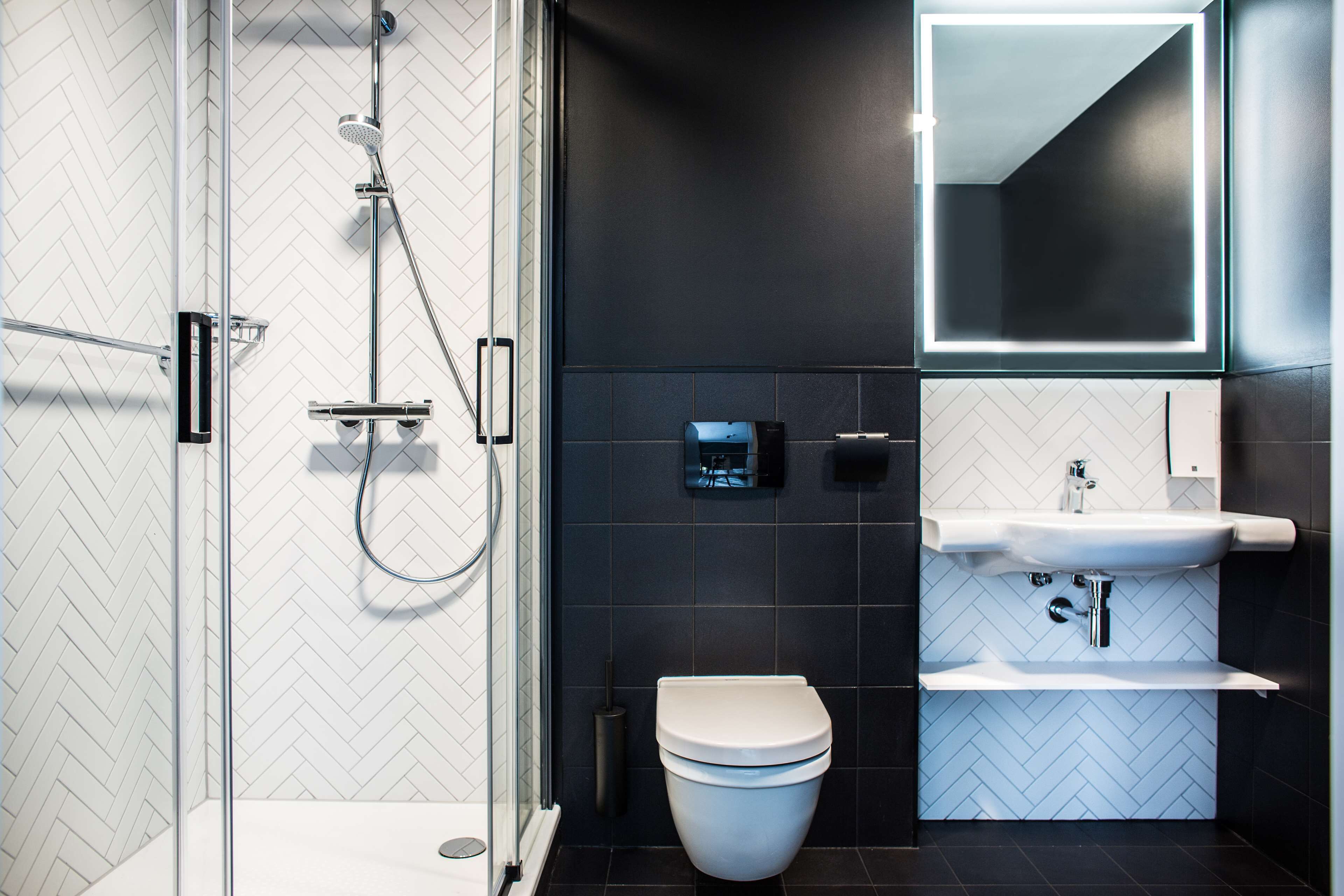 A modern bathroom with a glass-enclosed shower, a white toilet, and a sink with a mirror above it.
