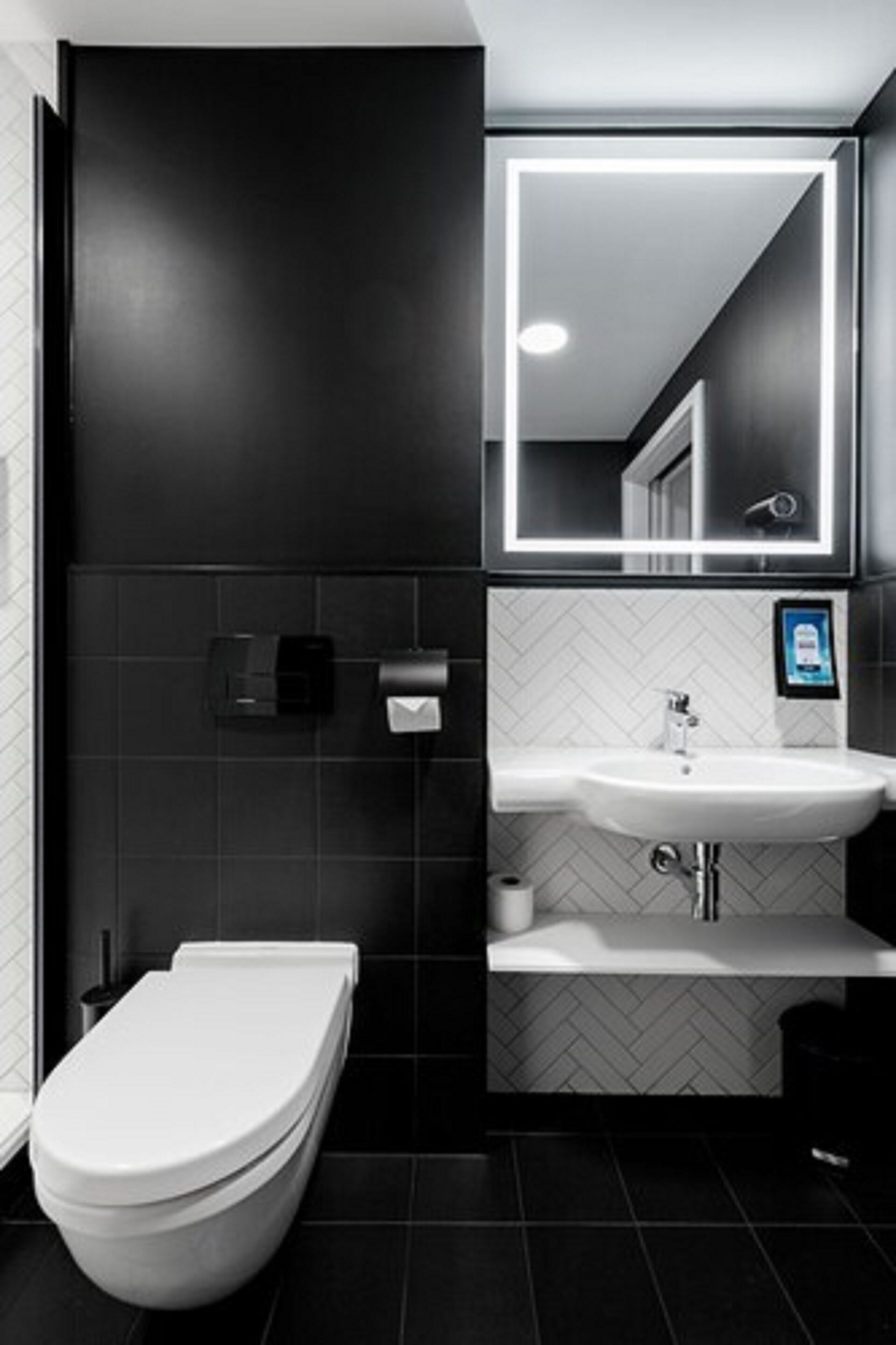 A modern bathroom with a toilet, sink, and mirror.