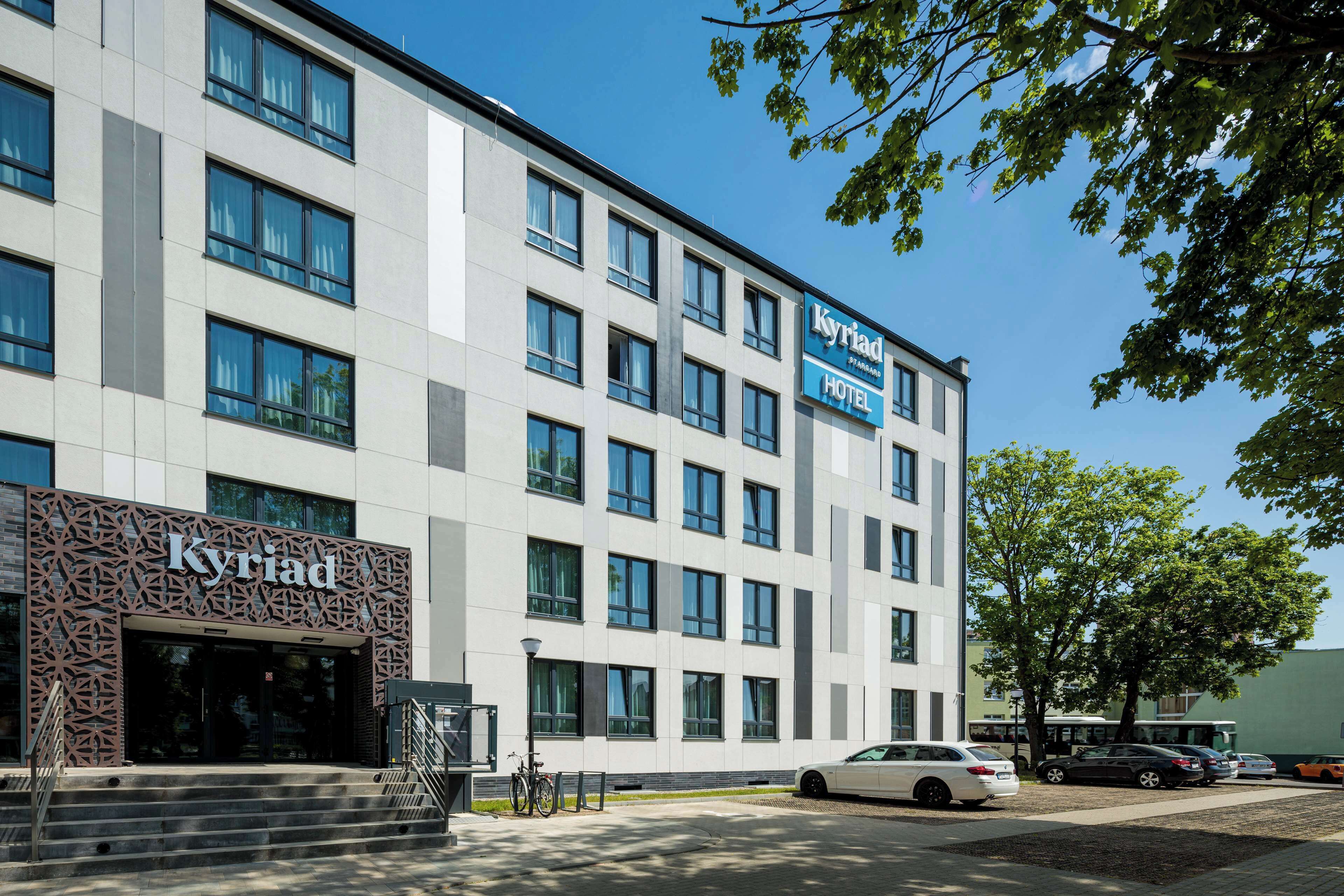 A modern hotel building with a clear entrance, multiple windows, and a sign indicating it is a hotel.
