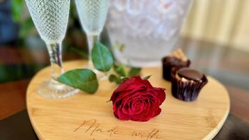 A wooden heart-shaped serving board with the inscription "Made with LOVE" and a red rose.
