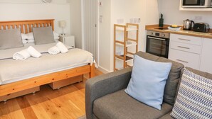A compact bedroom with a wooden bed, a small bedside table, and a built-in wardrobe. - The Mew (Dartmouth)